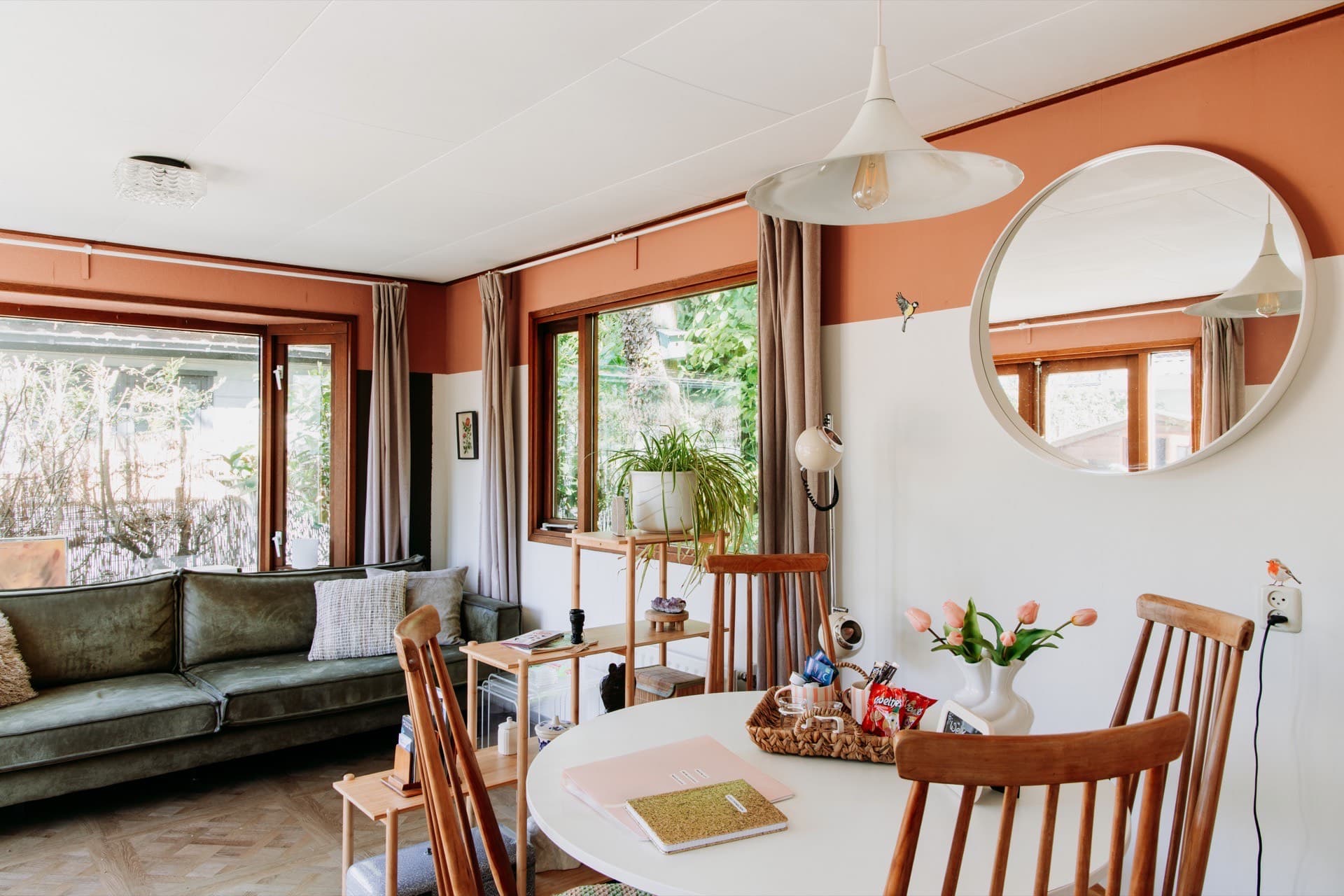 Woon-eetkamer van Chalet Olijfje met groene bank en ronde spiegel