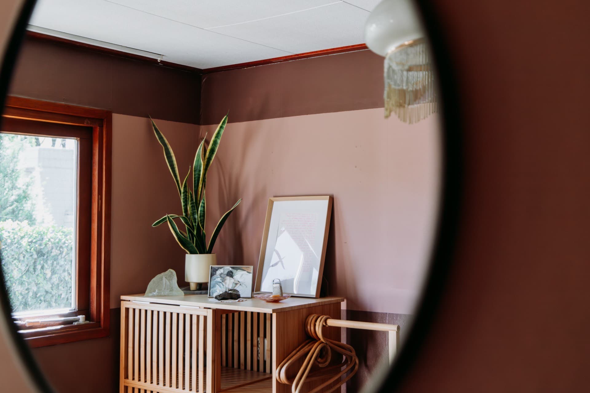 Spiegelzicht op dressoir met plant en kapstok in Chalet Olijfje